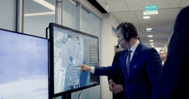 Pete Hegseth interacts with a touchscreen command-and-control system displaying real-time aerial surveillance data during a demonstration.