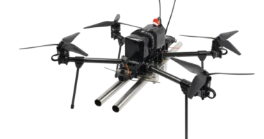 Fully assembled black quadcopter drone carrying a twin-barreled shotgun payload on a white background.