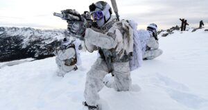 US Navy SEALs in winter warfare gear conducting tactical training in an Arctic environment, featuring Future Assault Shell Technology (FAST) helmets and specialized arctic combat equipment.