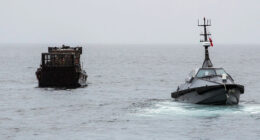 An autonomous surface vessel sea drone intercepts a cargo boat during a UK maritime security operation on open water