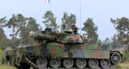 French Army Leclerc main battle tank draped in camouflage netting and flying the French tricolor during the Strong Europe Tank Challenge exercise, illustrating European armored warfare capability