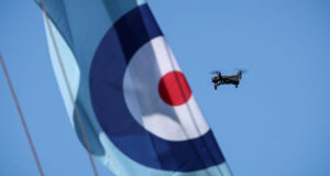 A compact quadcopter drone in flight alongside a Royal Air Force roundel banner during Exercise Agile Warrior, used to illustrate advances in quantum-resilient drone navigation and communications