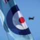 A compact quadcopter drone in flight alongside a Royal Air Force roundel banner during Exercise Agile Warrior, used to illustrate advances in quantum-resilient drone navigation and communications