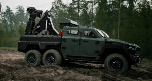 Inguar 4 military recovery vehicle with a rear-mounted lifting crane traversing muddy off-road terrain, designed for frontline equipment rescue operations