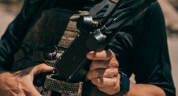 Soldier in tactical vest holding Neros Crossbow Block 2 wearable drone control station with multi-antenna array