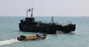 A Royal Navy LCU Mk10 landing craft and a vintage WWII DUKW amphibious vehicle flying the White Ensign flag during the D-Day 80th anniversary commemoration.